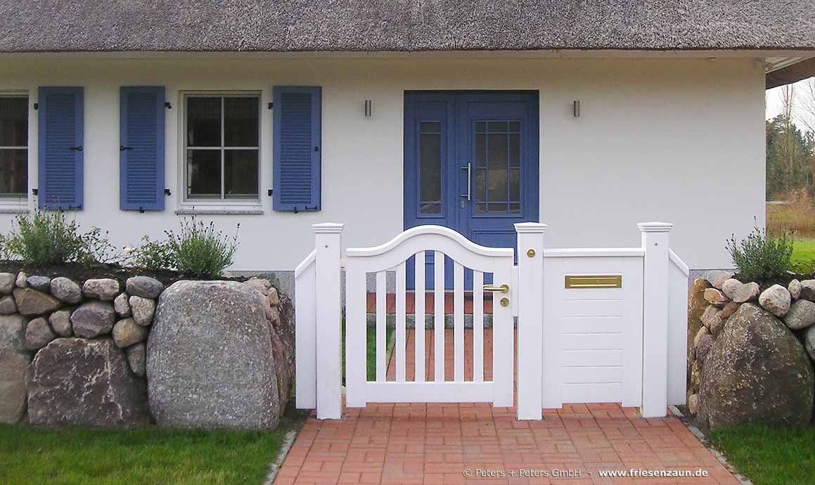 Wunderschönes Reetdachhaus mit einem typischem Friesenwall und einer weißen Gartentür mit Briefkasten.